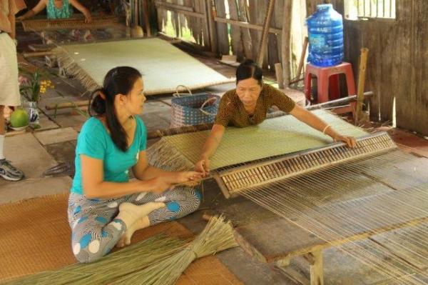 Women work to weave river-grass matting
